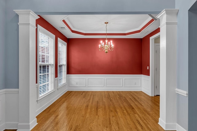 unfurnished dining area featuring a raised ceiling, light wood-type flooring, and ornamental molding