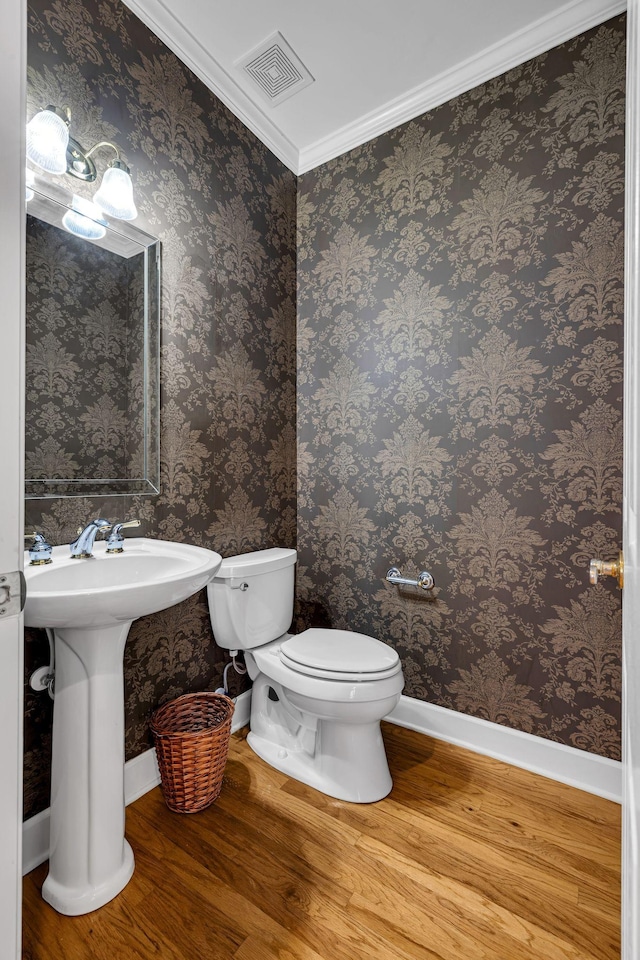 bathroom with hardwood / wood-style floors, toilet, and ornamental molding