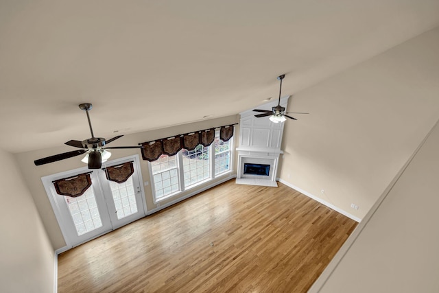 unfurnished living room featuring ceiling fan, a large fireplace, and light wood-type flooring