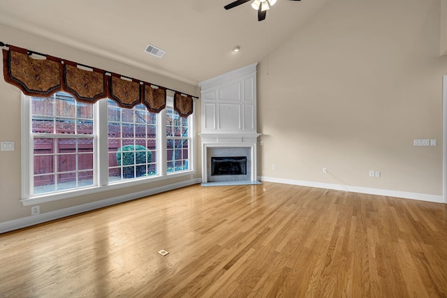 unfurnished living room featuring ceiling fan, a fireplace, vaulted ceiling, and light hardwood / wood-style flooring