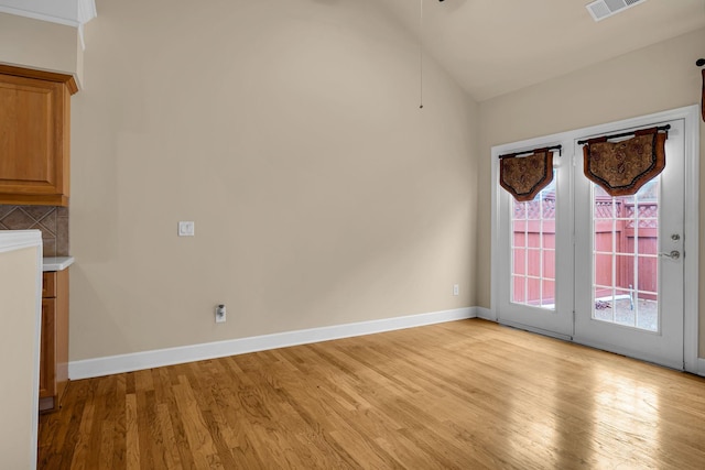 unfurnished dining area with light wood-type flooring and vaulted ceiling