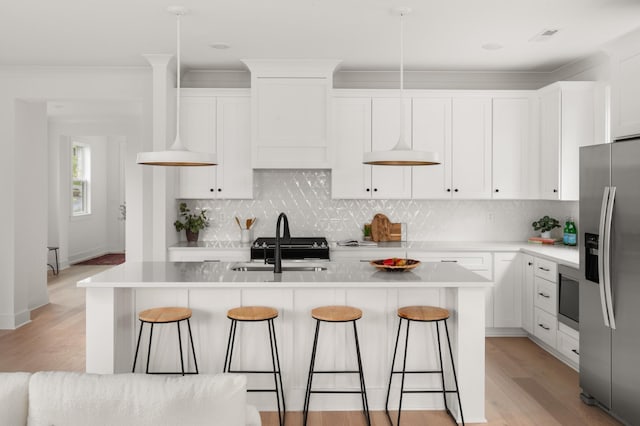 kitchen with white cabinetry, stainless steel fridge with ice dispenser, pendant lighting, and a kitchen island with sink