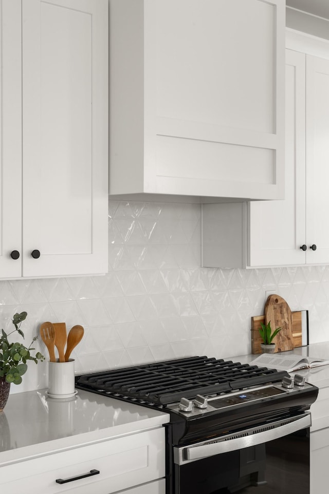 kitchen with tasteful backsplash, white cabinetry, and stainless steel gas range