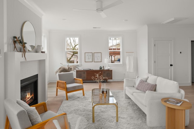 living room with ceiling fan, crown molding, and light hardwood / wood-style floors