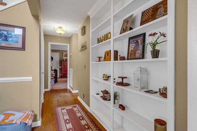 hall featuring hardwood / wood-style flooring, built in features, and a textured ceiling