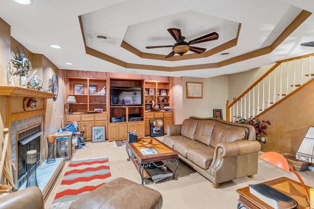 living room with built in features, carpet flooring, a raised ceiling, and ceiling fan