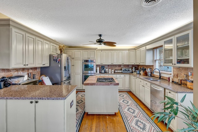 kitchen featuring sink, light hardwood / wood-style flooring, ceiling fan, butcher block countertops, and stainless steel appliances