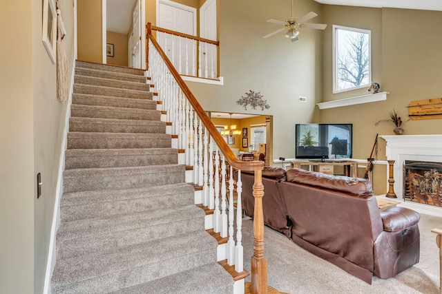 staircase featuring a towering ceiling and ceiling fan with notable chandelier