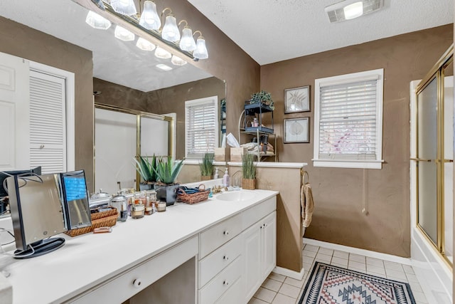 bathroom with tile patterned floors, plenty of natural light, a textured ceiling, and vanity