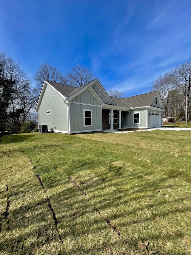 view of front facade featuring central air condition unit, board and batten siding, a front lawn, and a garage