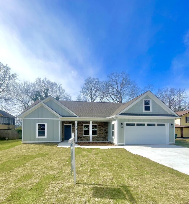 view of front of property with board and batten siding, a shingled roof, a front lawn, concrete driveway, and an attached garage