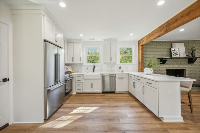 kitchen with kitchen peninsula, stainless steel appliances, sink, white cabinetry, and a breakfast bar area