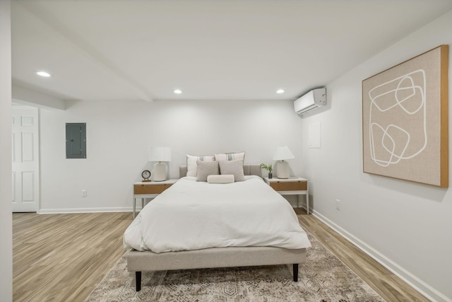 bedroom with a wall mounted air conditioner, light hardwood / wood-style floors, and electric panel