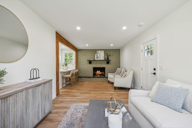 living room with light hardwood / wood-style flooring and a brick fireplace