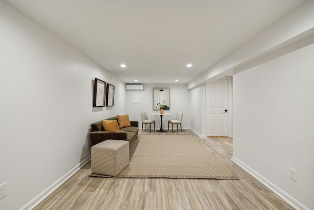 sitting room featuring a wall mounted air conditioner and light hardwood / wood-style flooring