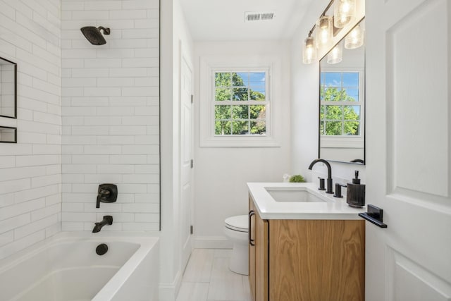 full bathroom with toilet, vanity, and tiled shower / bath