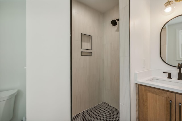 bathroom featuring a tile shower, vanity, and toilet