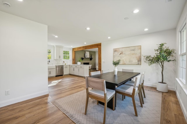 dining room with a brick fireplace, light hardwood / wood-style flooring, and sink