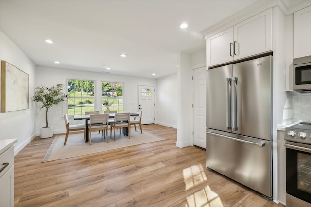 kitchen with stainless steel appliances, white cabinetry, tasteful backsplash, and light hardwood / wood-style flooring