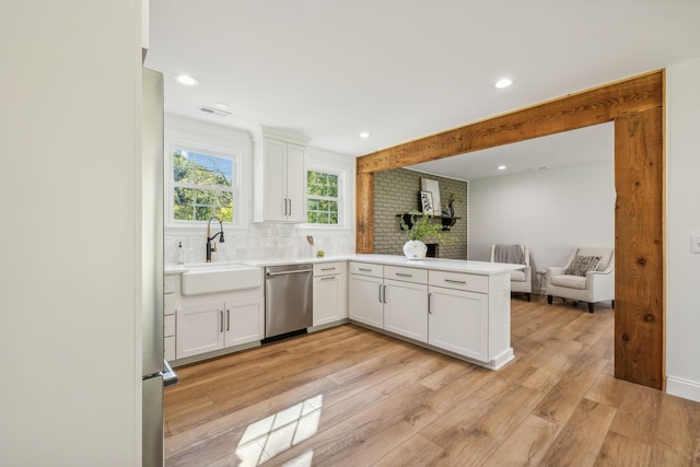 kitchen with dishwasher, sink, tasteful backsplash, kitchen peninsula, and white cabinets