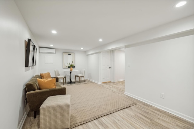 sitting room with a wall mounted AC and light hardwood / wood-style flooring