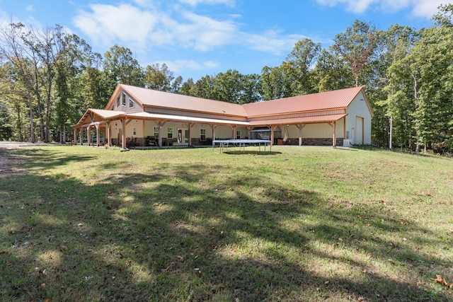 back of property with covered porch, a yard, a garage, and a trampoline