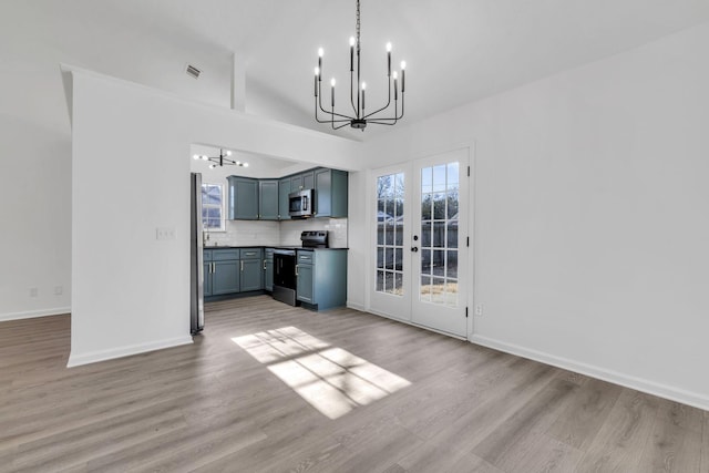 interior space with a notable chandelier, light hardwood / wood-style floors, lofted ceiling, and french doors