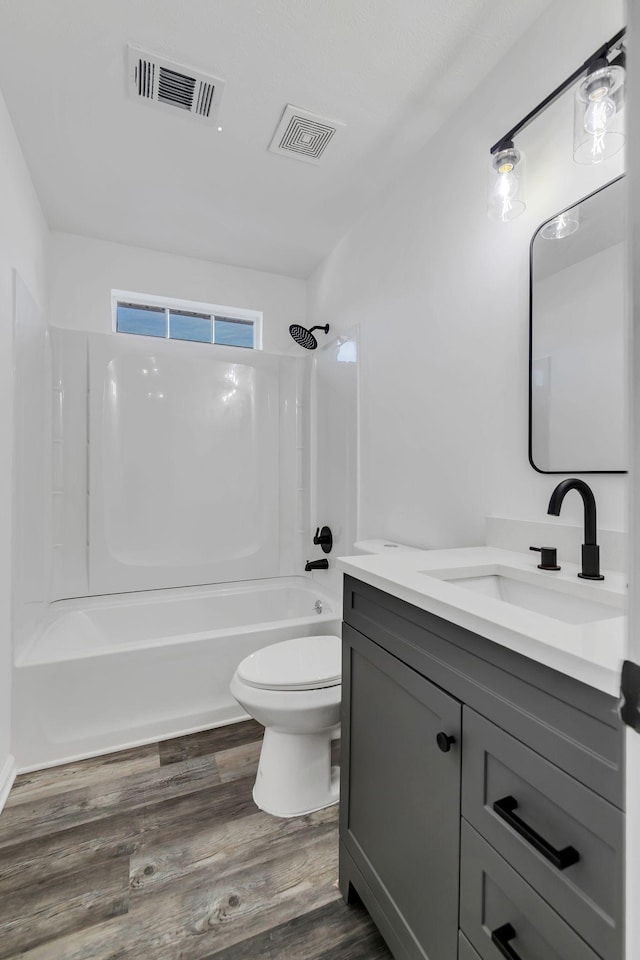 full bathroom with hardwood / wood-style flooring, vanity, toilet, and washtub / shower combination