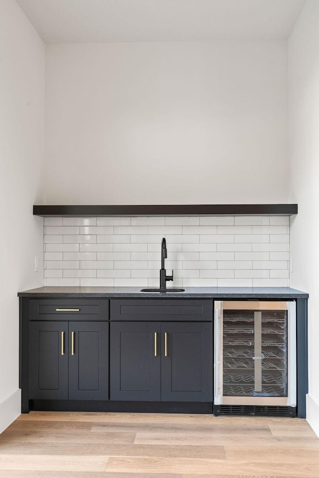 bar featuring sink, beverage cooler, and light hardwood / wood-style flooring