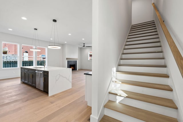 stairway with hardwood / wood-style flooring, ceiling fan, and sink