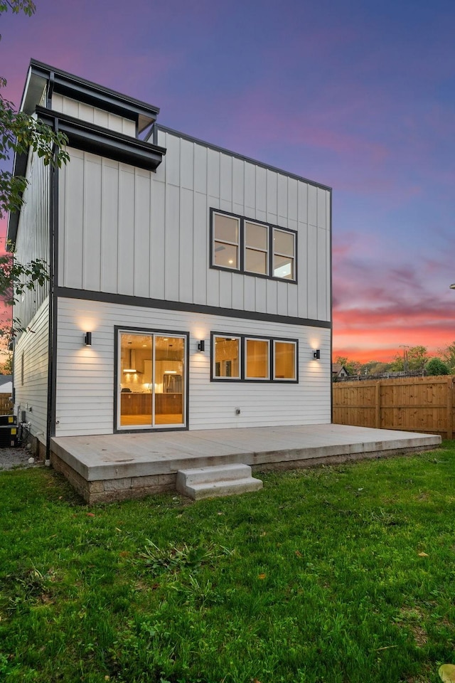 back house at dusk with a yard and a patio