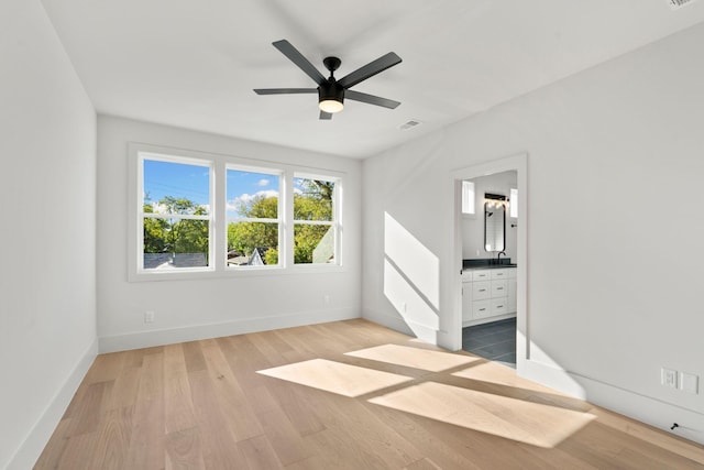 unfurnished bedroom featuring ensuite bath, ceiling fan, and light hardwood / wood-style flooring