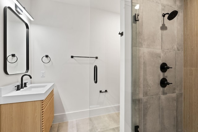 bathroom with tile patterned flooring, vanity, and a tile shower