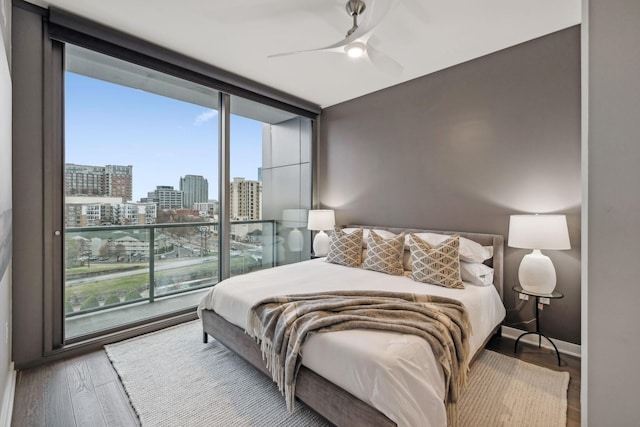 bedroom featuring ceiling fan, expansive windows, and hardwood / wood-style flooring