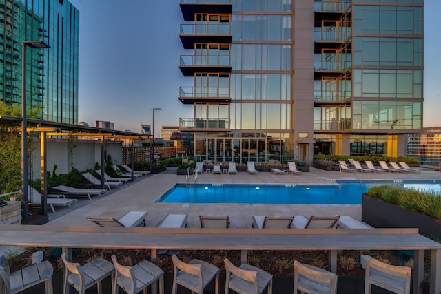 pool at dusk with a patio area