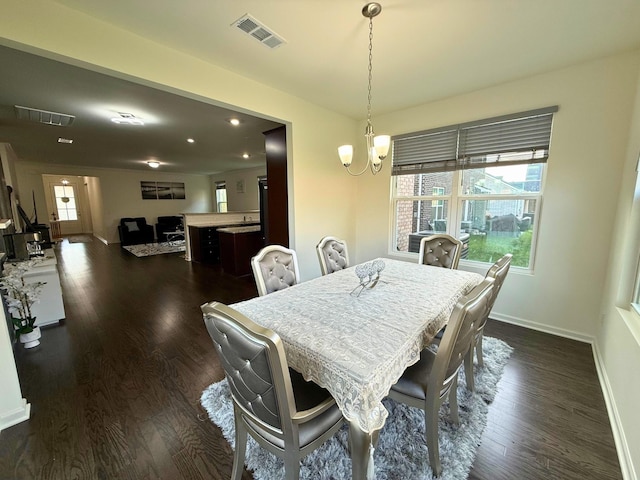 dining space with dark wood-type flooring and an inviting chandelier