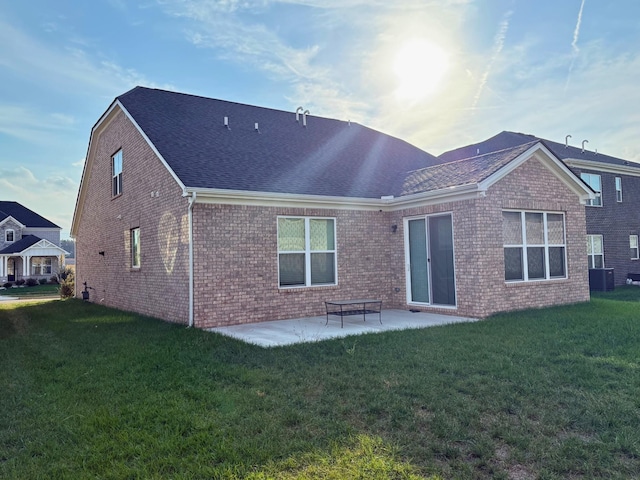 back of property with a lawn, central air condition unit, and a patio