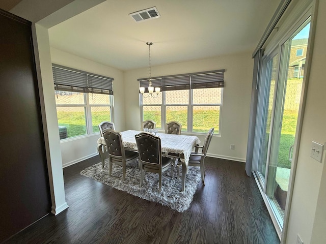 dining room featuring dark wood-type flooring, a wealth of natural light, and an inviting chandelier