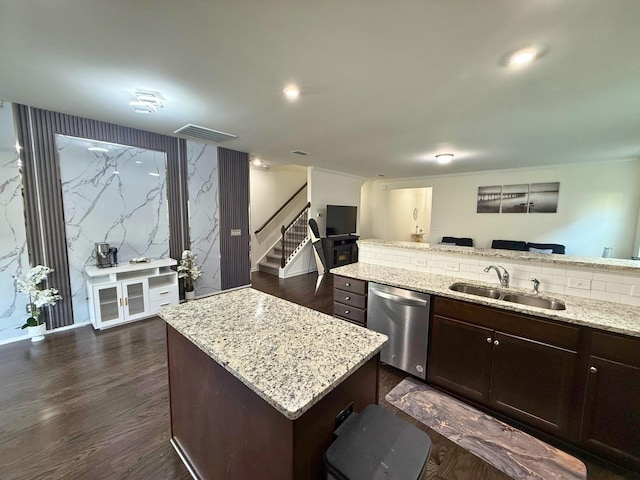 kitchen featuring dark brown cabinetry, sink, light stone counters, stainless steel dishwasher, and a kitchen island