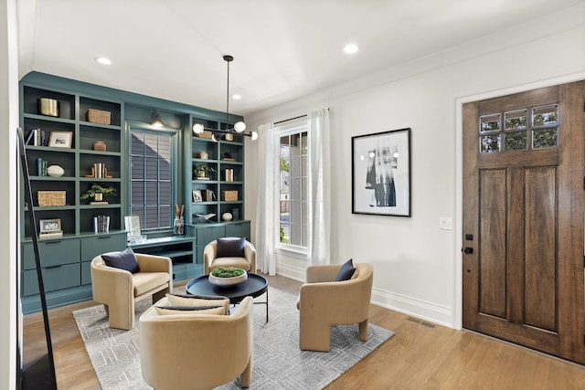 sitting room with hardwood / wood-style floors, built in features, and crown molding