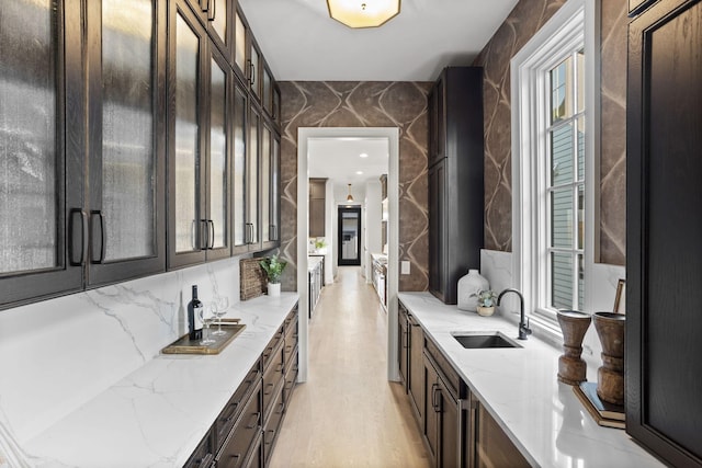 bar featuring light stone countertops, backsplash, tile walls, and sink