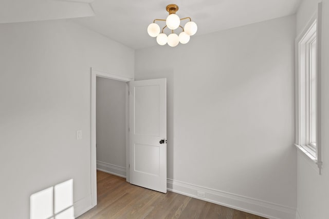 spare room with a notable chandelier and light hardwood / wood-style flooring