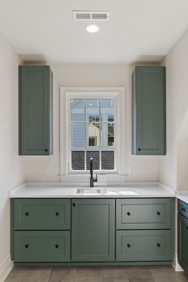 bar featuring sink and green cabinetry