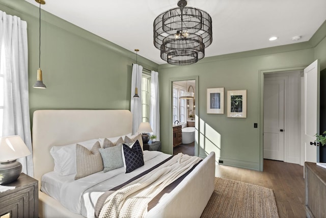 bedroom with dark hardwood / wood-style flooring, connected bathroom, and a chandelier