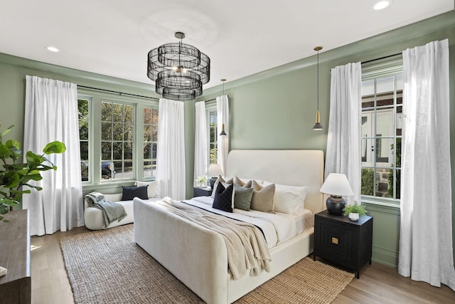 bedroom featuring hardwood / wood-style flooring, multiple windows, and a chandelier