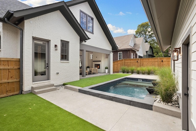 back of house featuring a fenced in pool, an outdoor fireplace, and a patio