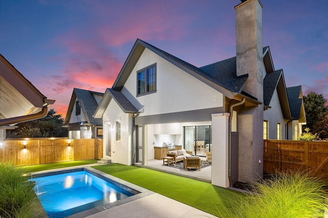 back house at dusk with a fenced in pool, outdoor lounge area, and a patio