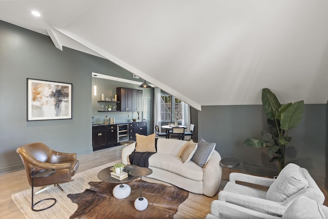 living room with light hardwood / wood-style floors, indoor bar, wine cooler, and vaulted ceiling