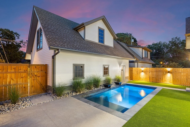 back house at dusk featuring a fenced in pool, a patio area, and a yard