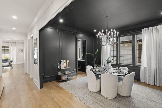 dining area with crown molding, light hardwood / wood-style flooring, and a notable chandelier